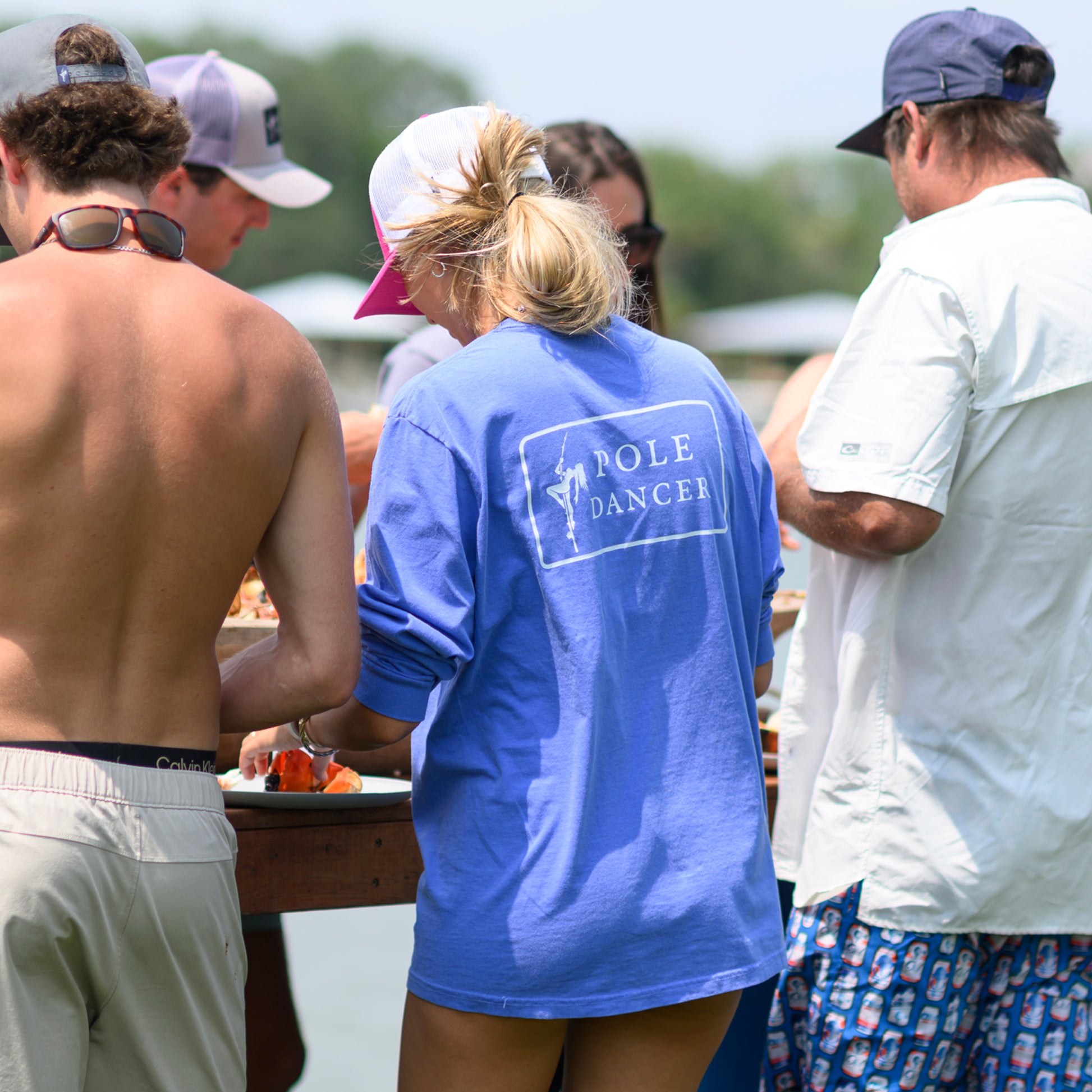 The back of a woman wearing the Flo Blue Pole Dancer long sleeve Alpha Pocket T Shirt while at a Lowcountry boil.