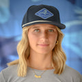 Woman wearing a marlin Pole Dancer Diamond Rope hat in front of a lurred blue backdrop.