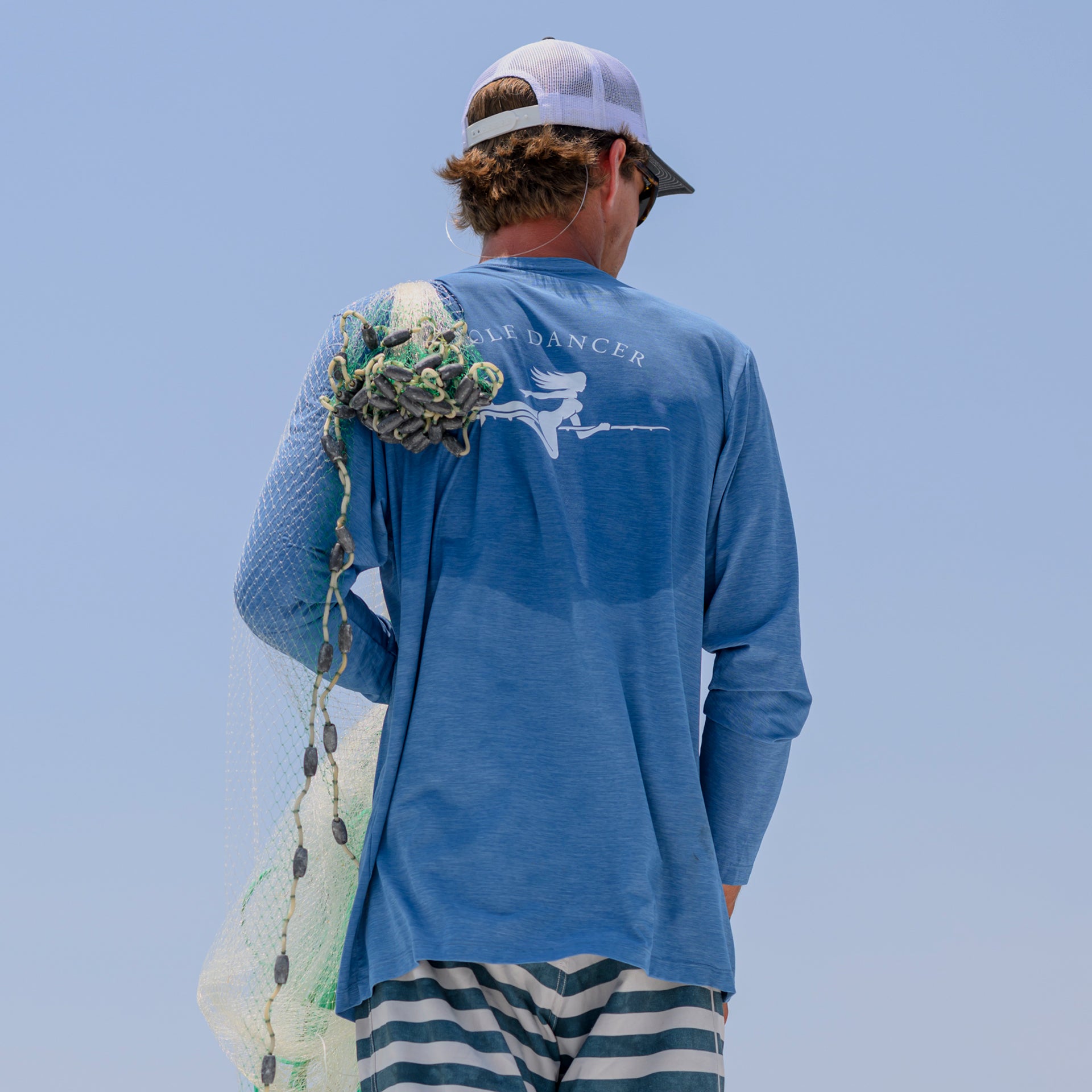Man wearing a Pole Dancer Bahama/Heather Riding East Performance Long Sleeve Performance shirt with a fishing net draped over his shoulder.