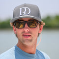 Man wearing the Pole Dancer Large PD Rope Hat and sunglasses on a boat with water in the background.
