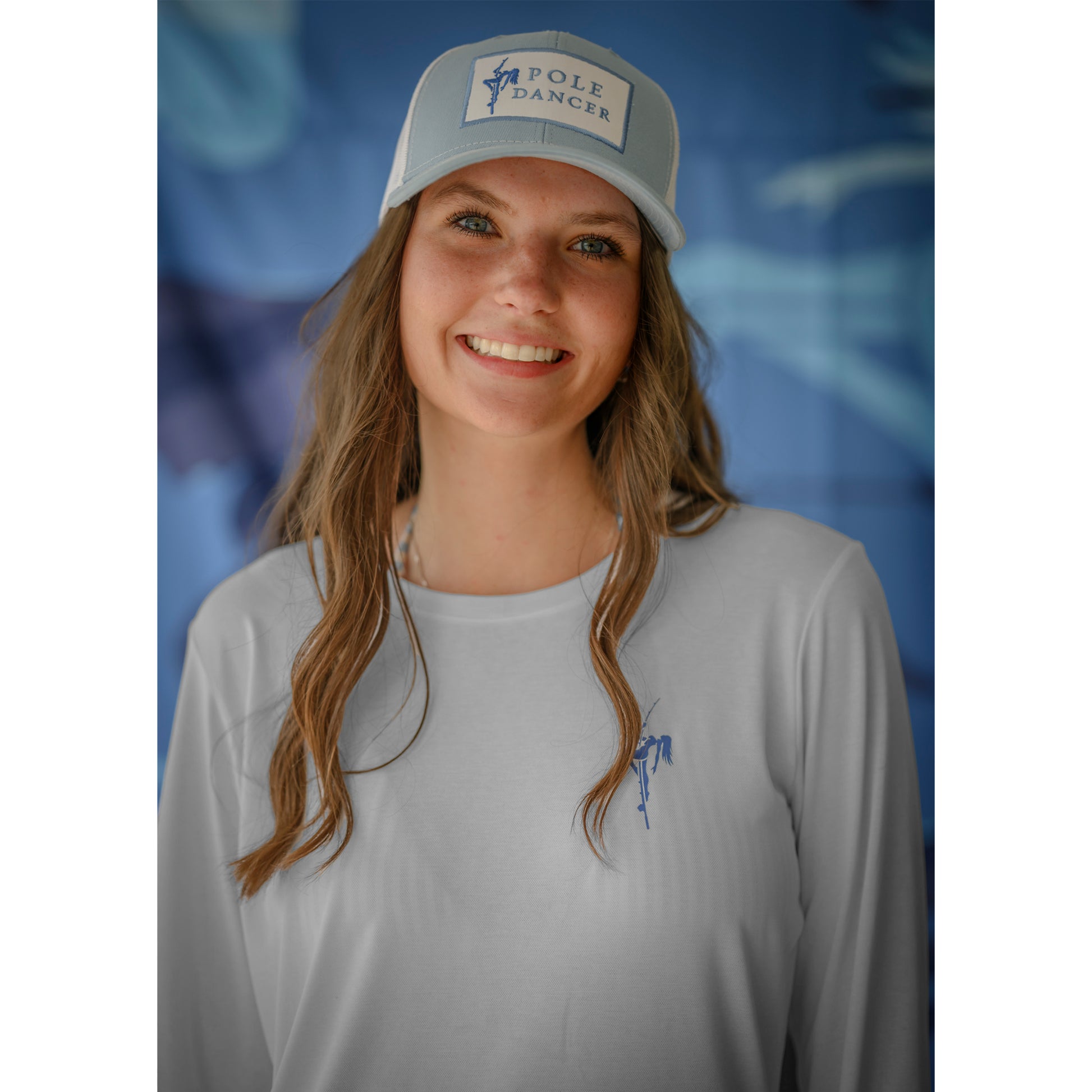 Woman smiling while wearing the Pole Dancer Women's Alpha Performance Long Sleeve in front of a blue backdrop.